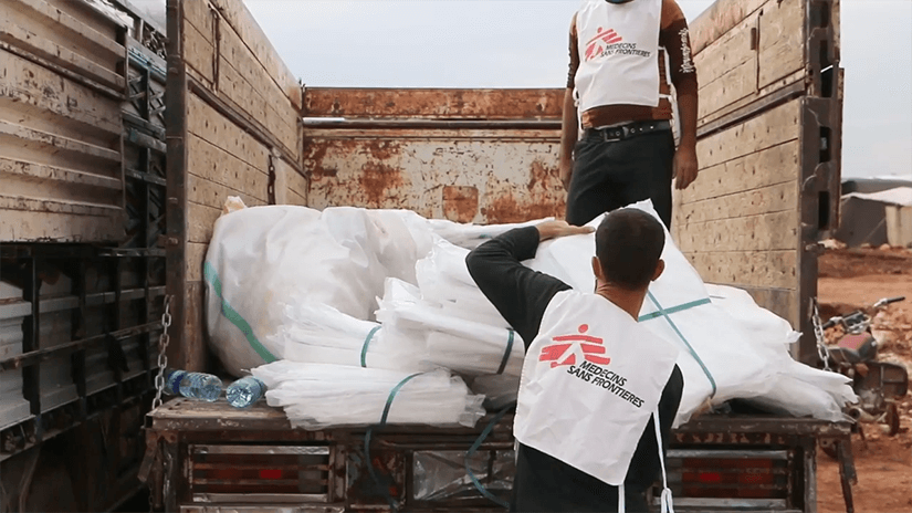 Worker lifting supplies from a truck wearing a Médecins Sans Frontières vest