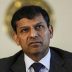 Raghuram Rajan in a suit. Behind him is a blurred dial on a white background
